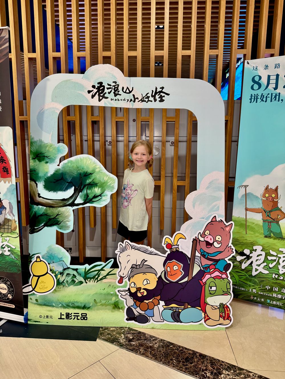 Lily stands inside a large cardboard photo cutout for the Chinese animated film Nobody's Monster at a cinema in Shanghai fall 2025