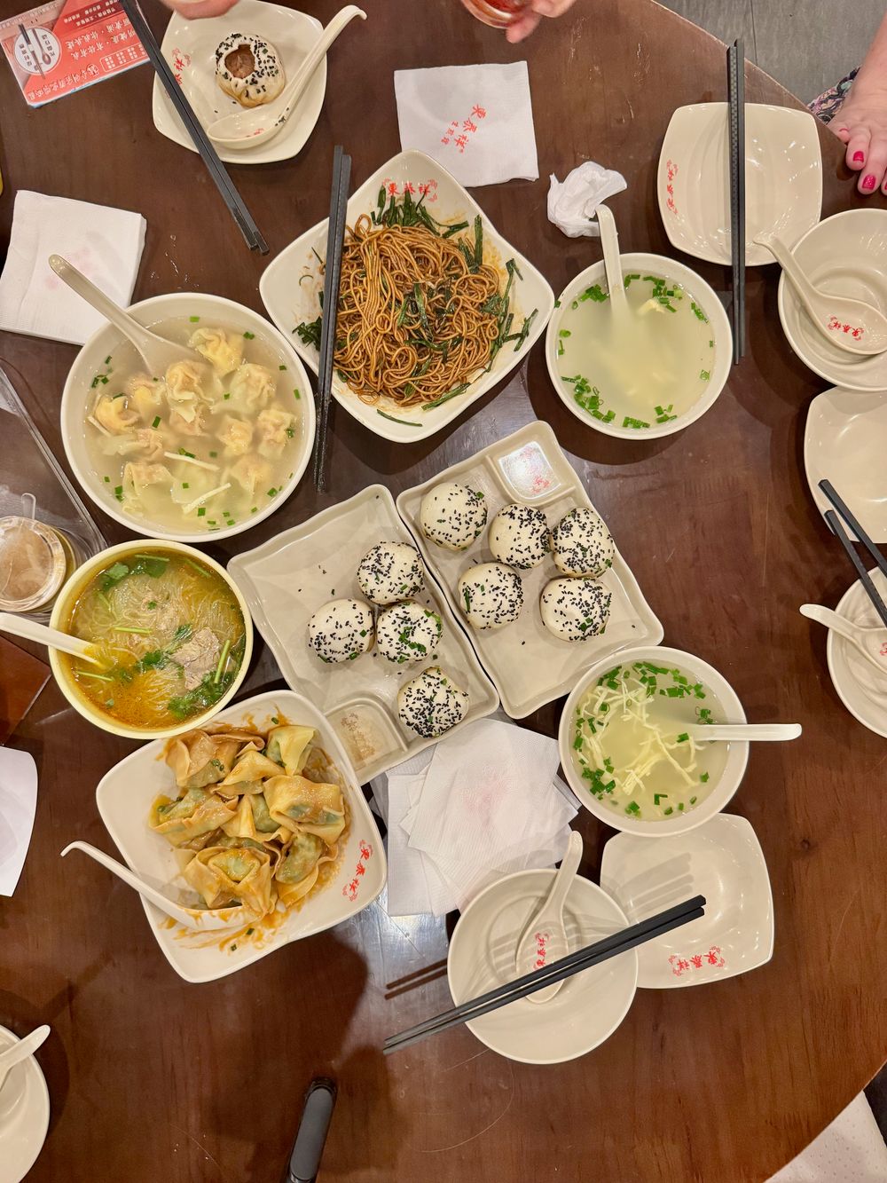 Round wooden table covered in Shanghai food tour dishes including wontons, dumplings, sesame balls, and noodles in Dapuqiao fall 2025