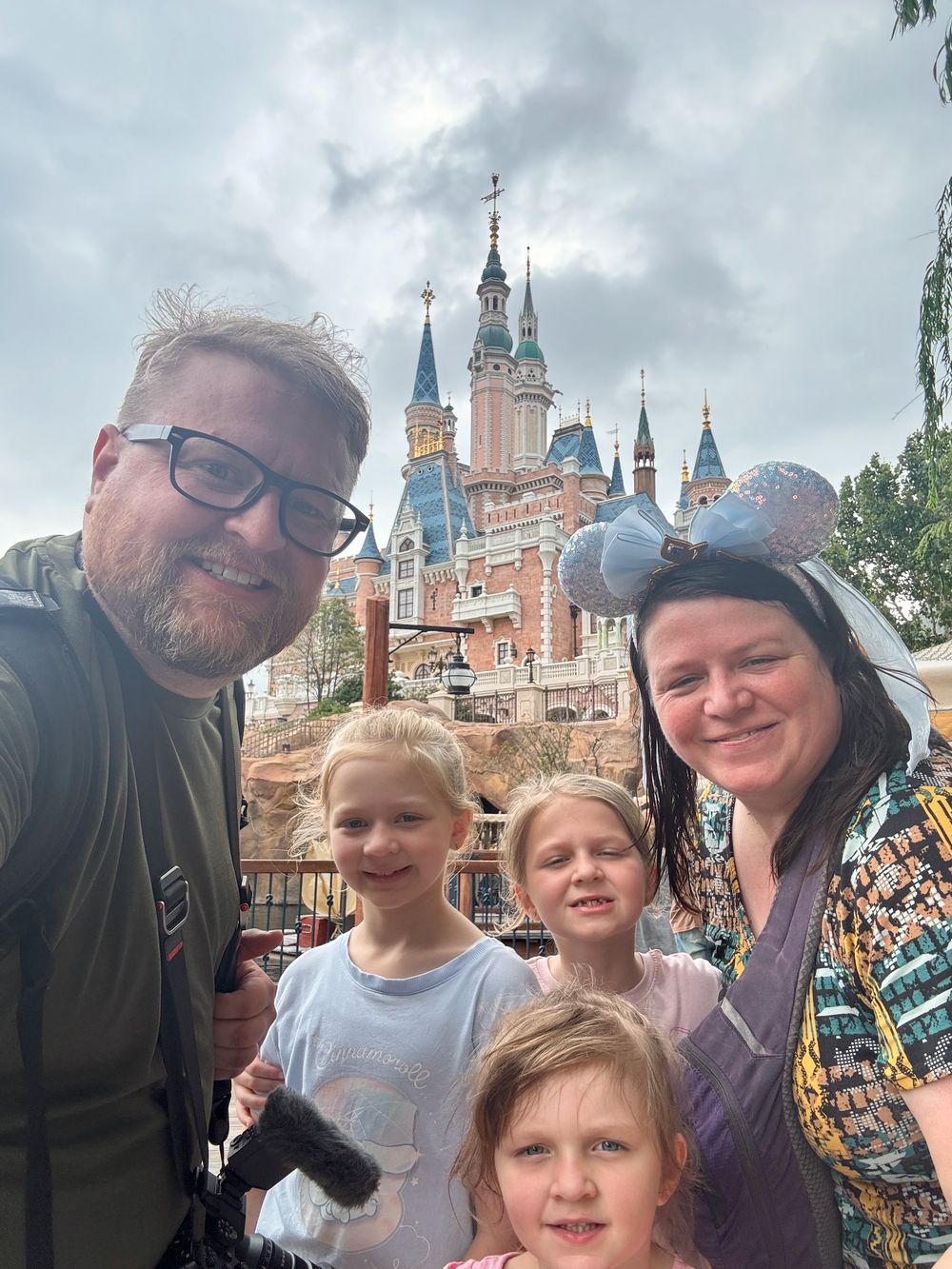 Family selfie at the Enchanted Storybook Castle at Shanghai Disneyland, all five family members, fall 2025