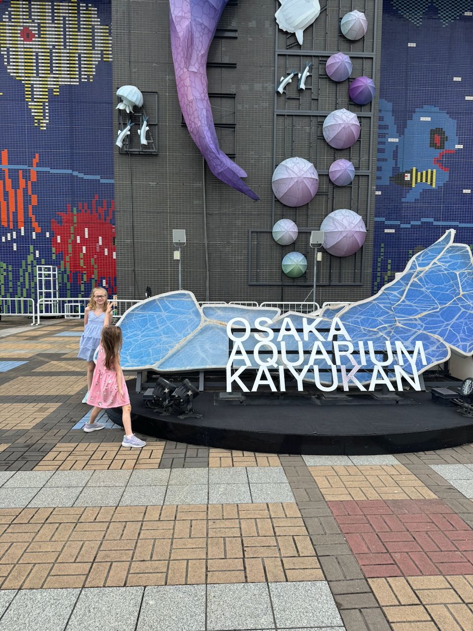 Harper and Lily at the whale shark entrance sign of Osaka Aquarium Kaiyukan