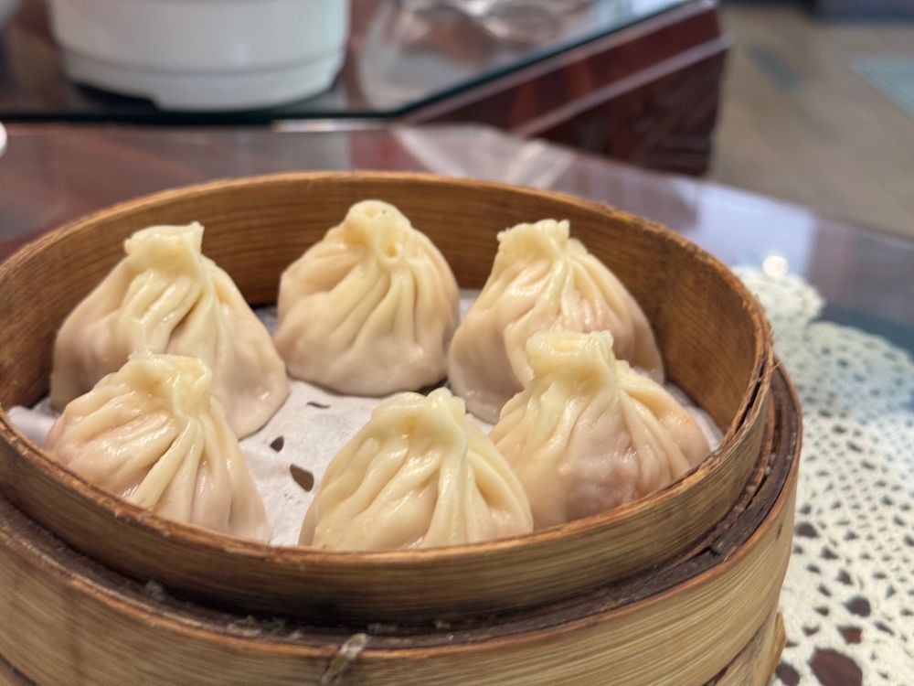 Six steamed xiaolongbao in a bamboo steamer basket at a Jing'an District restaurant.