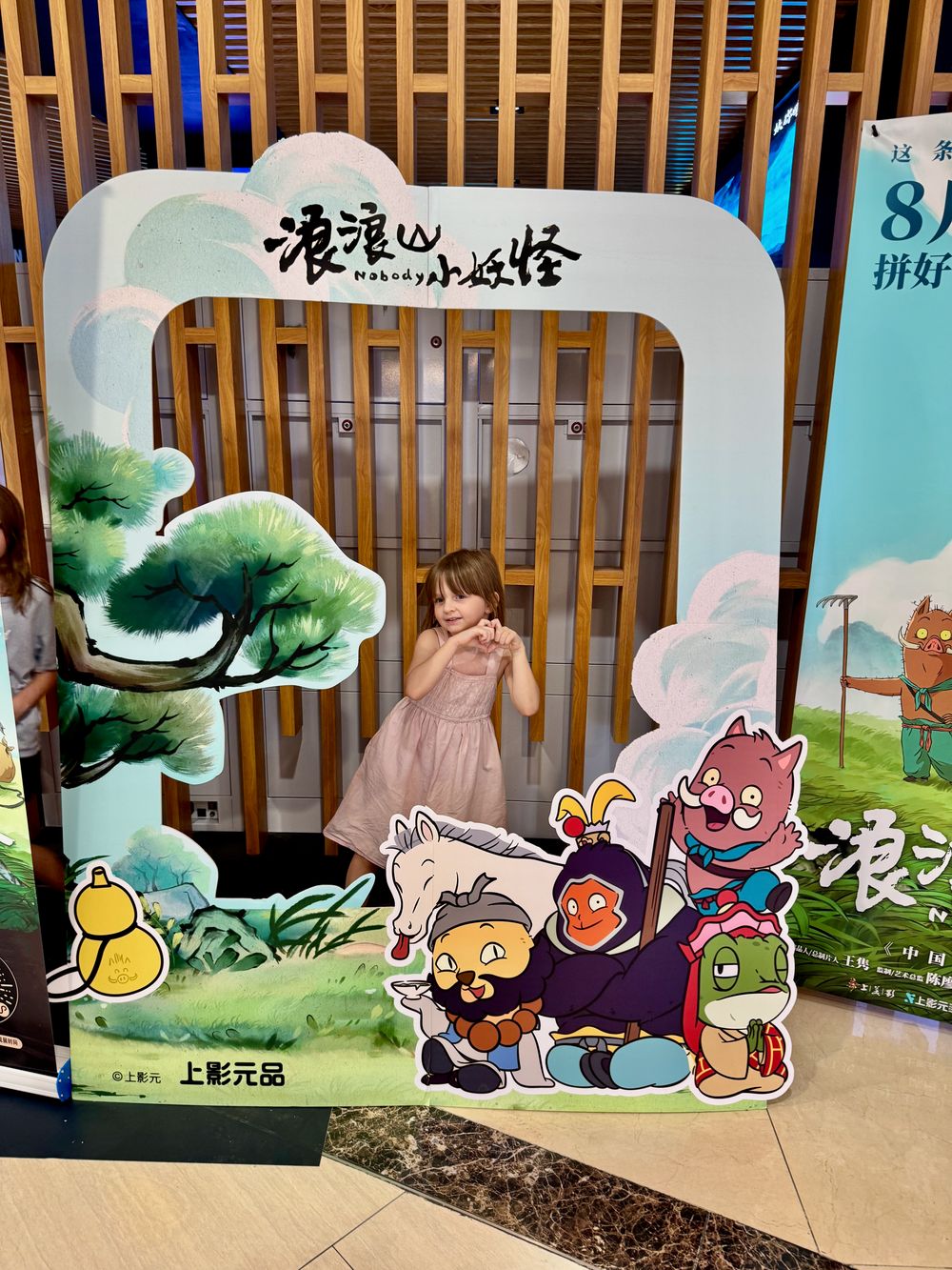 Harper in a pink dress posing inside a large cardboard photo cutout for the Chinese animated film Nobody at a cinema in Pudong Shanghai fall 2025