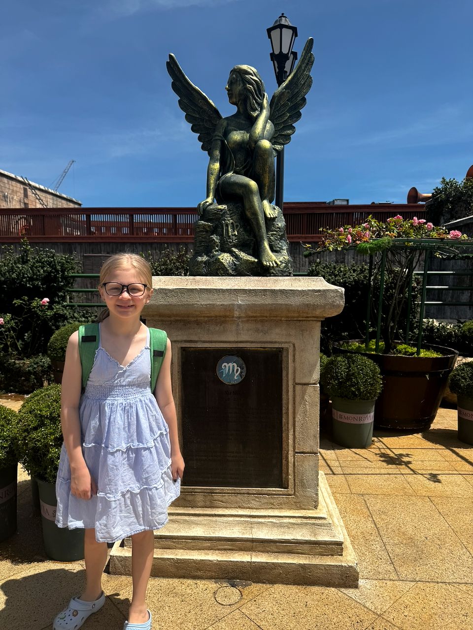 Lily with her green backpack in front of the winged Virgo zodiac statue at Ba Na Hills Rose Garden