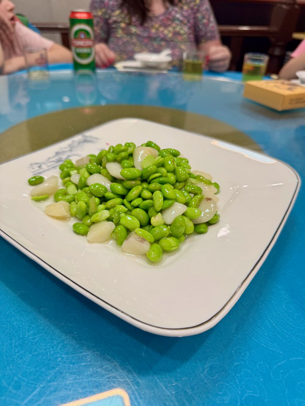 White square plate of stir-fried edamame and water chestnuts on a blue tablecloth at a restaurant in Xuhui District Shanghai