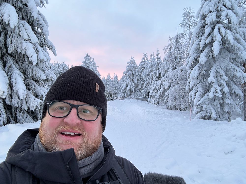 Adam on a snow-covered forest road outside Rovaniemi under a pink Arctic sky