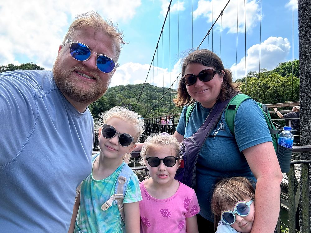 All five Clarksons in sunglasses taking a selfie on the suspension bridge at Xinliao Village in New Taipei, jungle hills visible behind them
