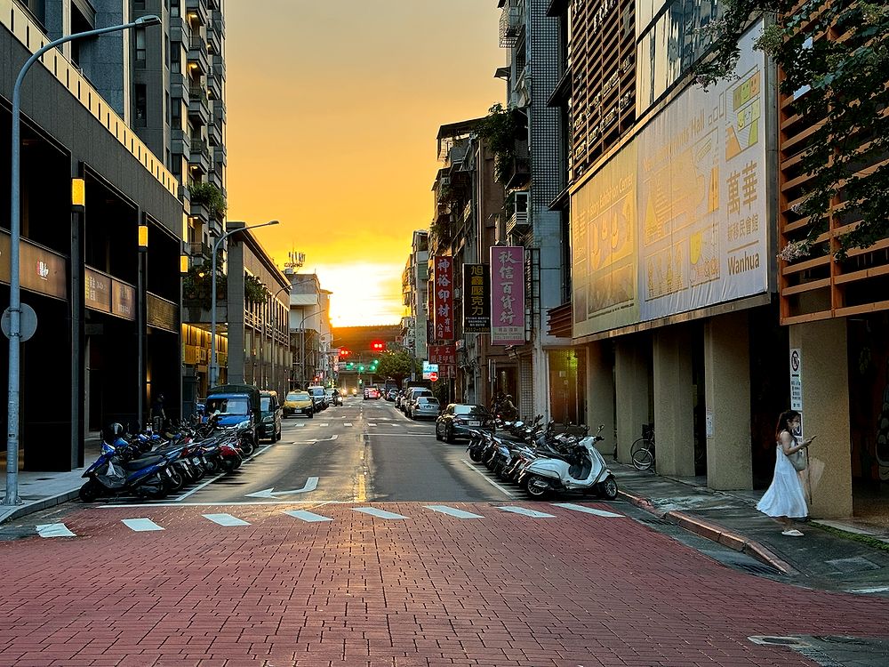 The sunset lined up perfectly with the street in Wanhua, scooters parked on both sides, sky on fire.
